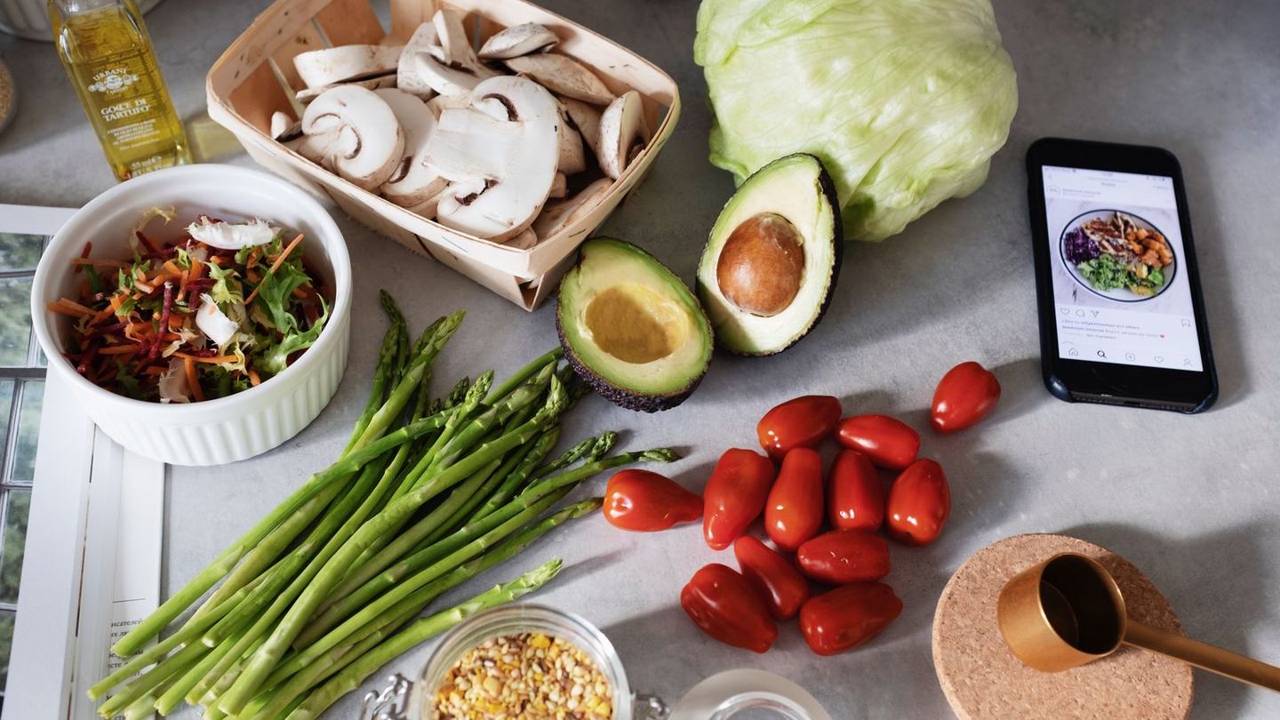Friske råvarer som asparges, tomater, avocado og svampe på et køkkenbord